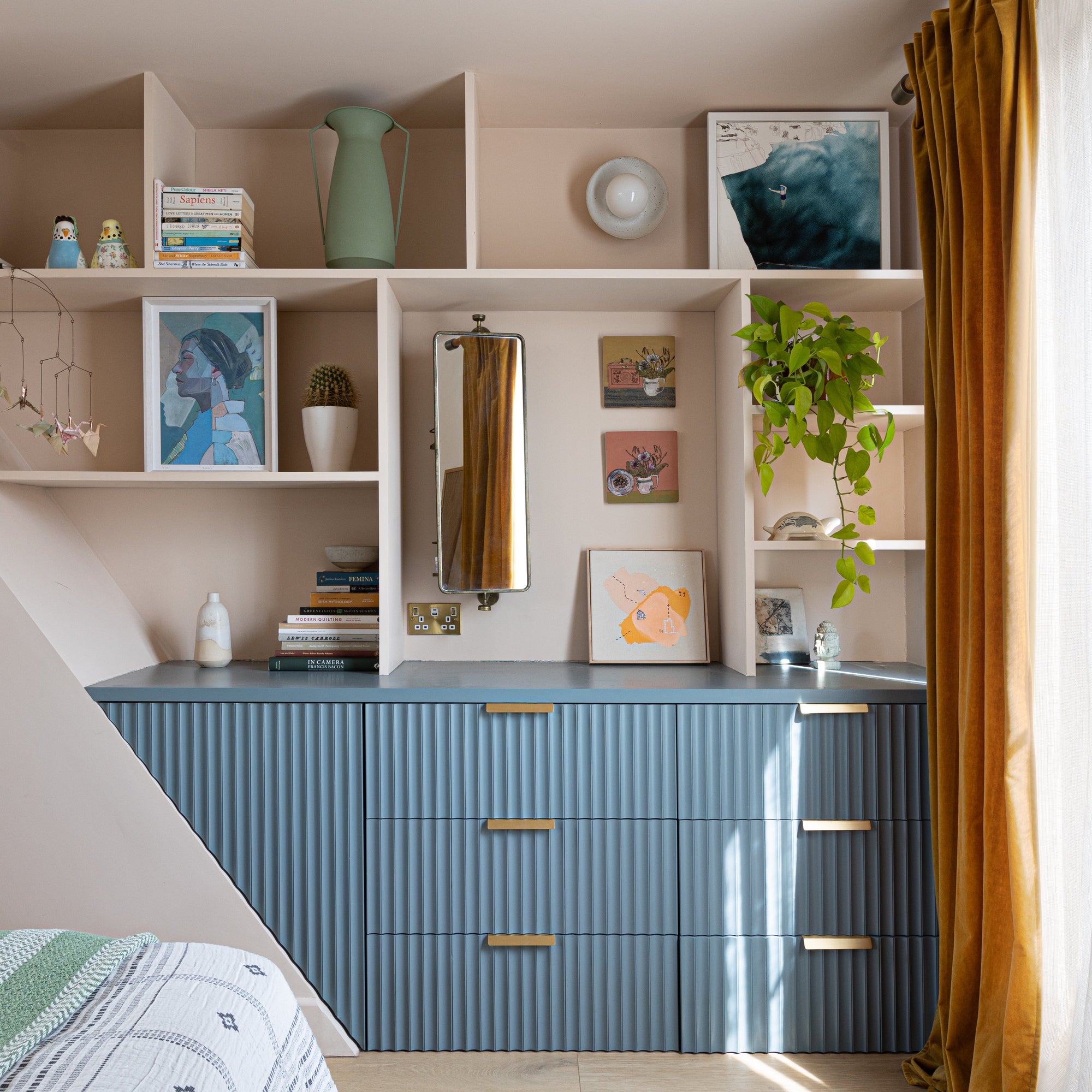 Modern bedroom with blue dresser, shelves, ceramic wall light and decorative items.