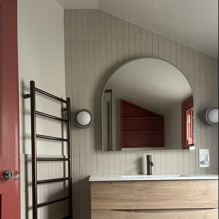 Bathroom interior with wooden vanity, round mirror, Ceramic lights and red door.
