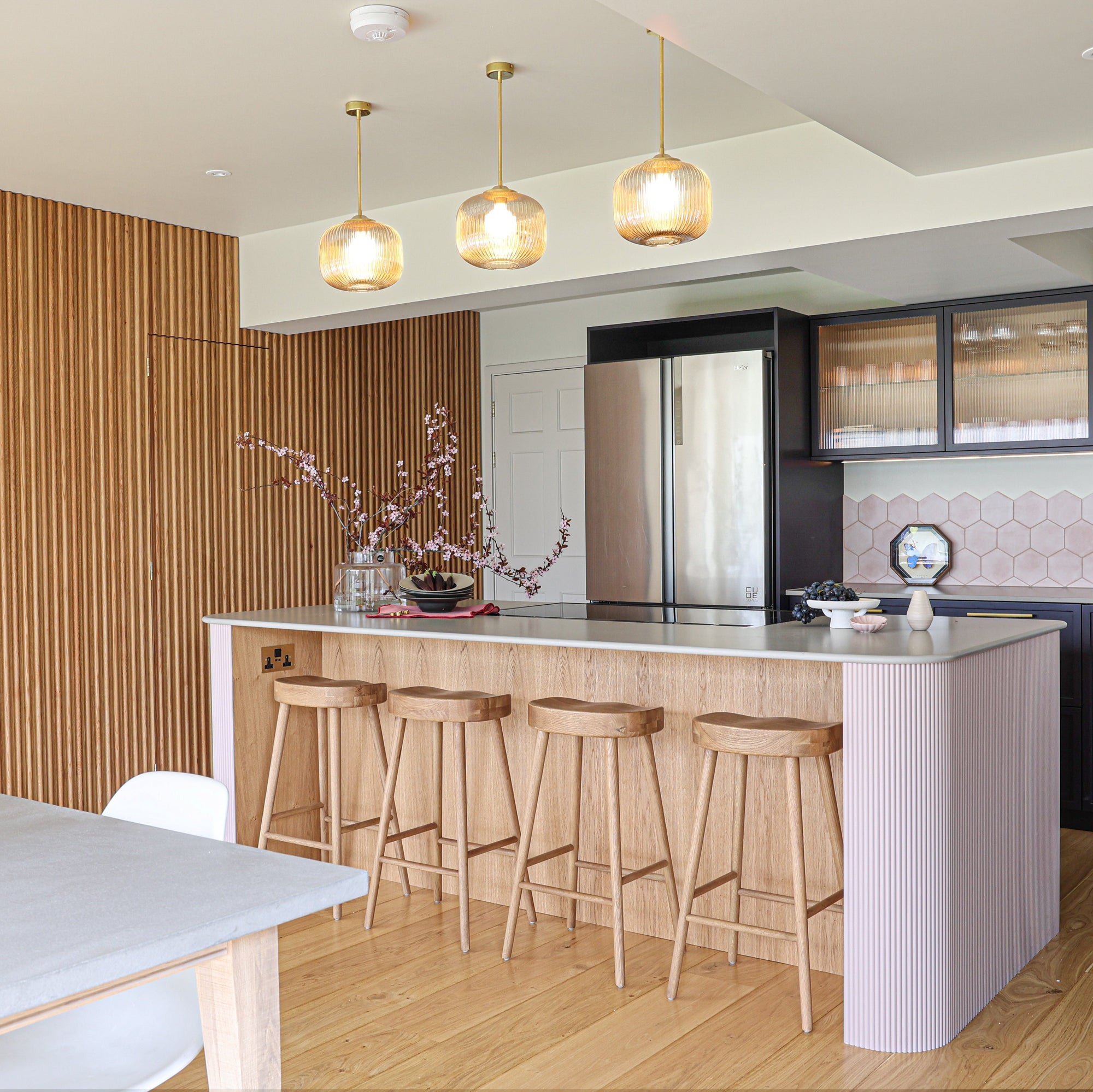 Modern kitchen with island, bar stools, and decorative glass lighting.