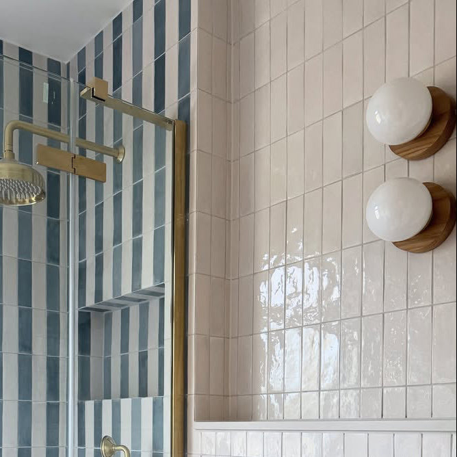 Modern shower setup with gold fixtures and striped tiles in a bathroom and wooden opal lights