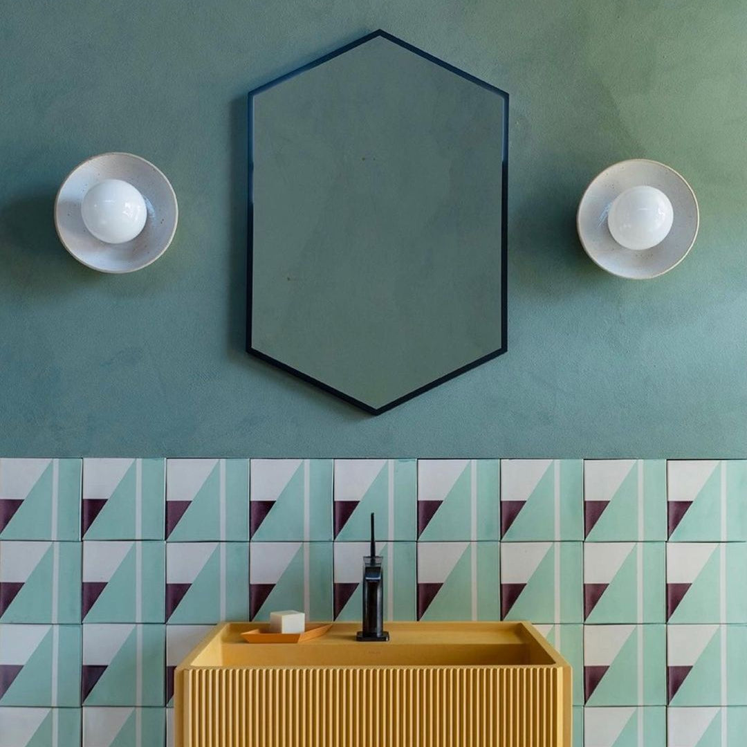 Bathroom with geometric tile pattern, hexagonal mirror, and yellow sink.