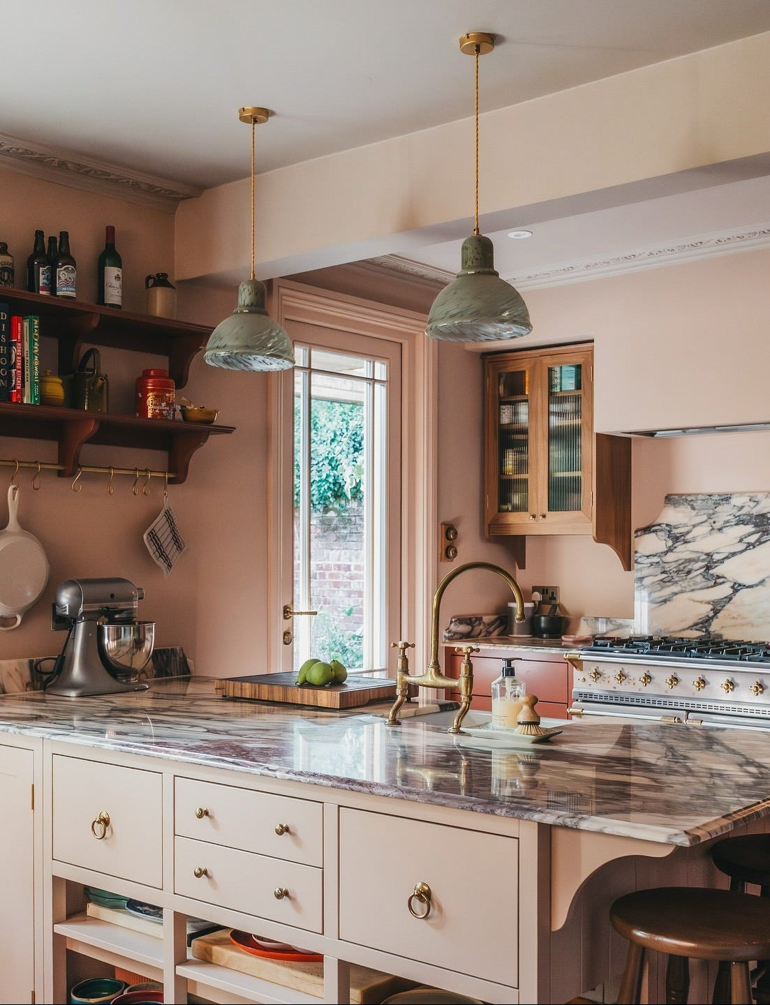 Modern kitchen with wooden cabinets, marble countertops, glass pendants and stainless steel appliances.