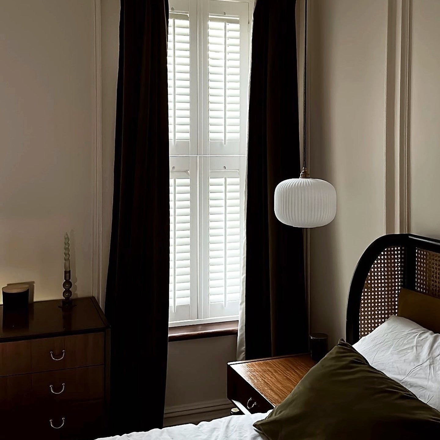 reeded pendant Bedroom with dark curtains, wooden nightstands, and a lamp